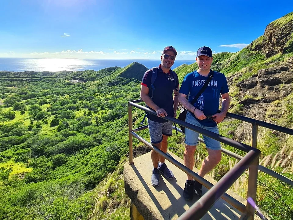 Cruising with Danny and Peter, Holland America Line, Koningsdam, Honolulu, Hawaii, United States | Breathtaking views from the Diamond Head summit during the hike, showcasing scenic views of Honolulu and Waikiki Beach, capturing the essence of volcano hiking in Hawaii, followed by a vibrant scene from Germaine's Luau, highlighting traditional Hawaiian feast, cultural events in Hawaii, and mesmerizing Hawaiian dance performances, all reflecting the rich Polynesian culture and Hawaiian hospitality.
