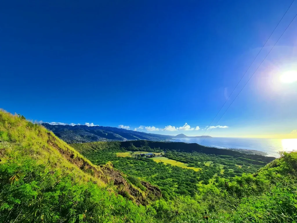 Cruising with Danny and Peter, Holland America Line, Koningsdam, Honolulu, Hawaii, United States | Breathtaking views from the Diamond Head summit during the hike, showcasing scenic views of Honolulu and Waikiki Beach, capturing the essence of volcano hiking in Hawaii, followed by a vibrant scene from Germaine's Luau, highlighting traditional Hawaiian feast, cultural events in Hawaii, and mesmerizing Hawaiian dance performances, all reflecting the rich Polynesian culture and Hawaiian hospitality.