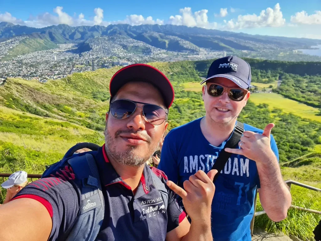 Cruising with Danny and Peter, Holland America Line, Koningsdam, Honolulu, Hawaii, United States | Breathtaking views from the Diamond Head summit during the hike, showcasing scenic views of Honolulu and Waikiki Beach, capturing the essence of volcano hiking in Hawaii, followed by a vibrant scene from Germaine's Luau, highlighting traditional Hawaiian feast, cultural events in Hawaii, and mesmerizing Hawaiian dance performances, all reflecting the rich Polynesian culture and Hawaiian hospitality.