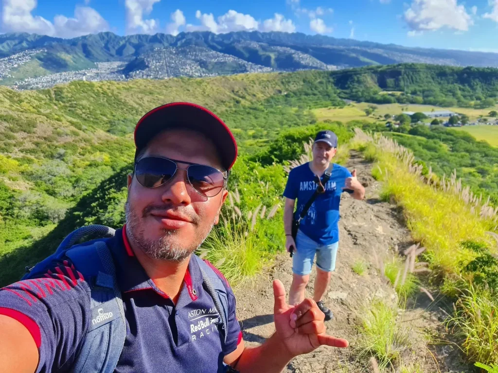 Cruising with Danny and Peter, Holland America Line, Koningsdam, Honolulu, Hawaii, United States | Breathtaking views from the Diamond Head summit during the hike, showcasing scenic views of Honolulu and Waikiki Beach, capturing the essence of volcano hiking in Hawaii, followed by a vibrant scene from Germaine's Luau, highlighting traditional Hawaiian feast, cultural events in Hawaii, and mesmerizing Hawaiian dance performances, all reflecting the rich Polynesian culture and Hawaiian hospitality.