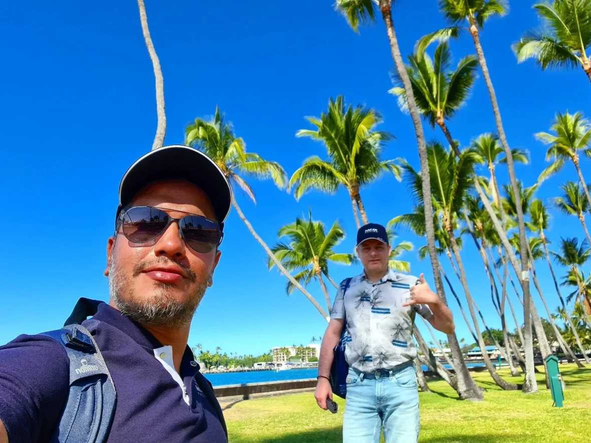 Cruising with Danny and Peter, Holland America Line, Koningsdam, Kona, Hawaii, United-States | A vibrant scene showcasing the beauty of Kona Hawaii, featuring secluded beaches with soft sand and crystal-clear waters, colorful storefronts along the bustling streets, and breathtaking scenic views of the Kona coast during sunset. The image captures the essence of Exploring Kona's Island Charm, highlighting local culture with hula dancers and delicious Hawaiian cuisine served at a beachfront restaurant.