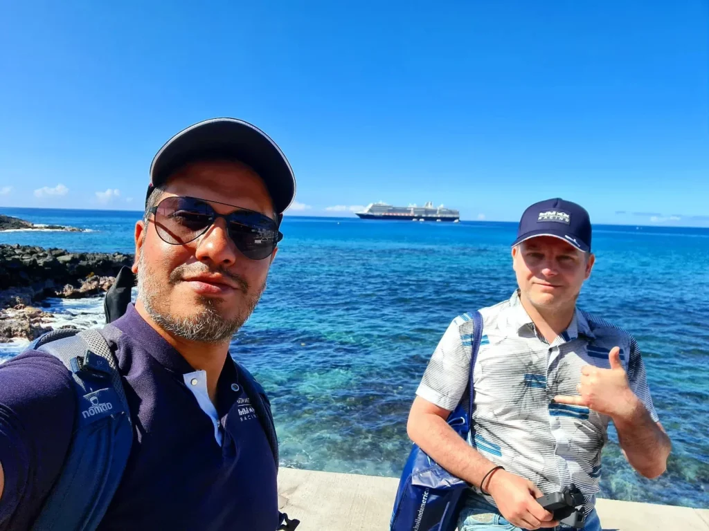 Cruising with Danny and Peter, Holland America Line, Koningsdam, Kona, Hawaii, United-States | A vibrant scene showcasing the beauty of Kona Hawaii, featuring secluded beaches with soft sand and crystal-clear waters, colorful storefronts along the bustling streets, and breathtaking scenic views of the Kona coast during sunset. The image captures the essence of Exploring Kona's Island Charm, highlighting local culture with hula dancers and delicious Hawaiian cuisine served at a beachfront restaurant.