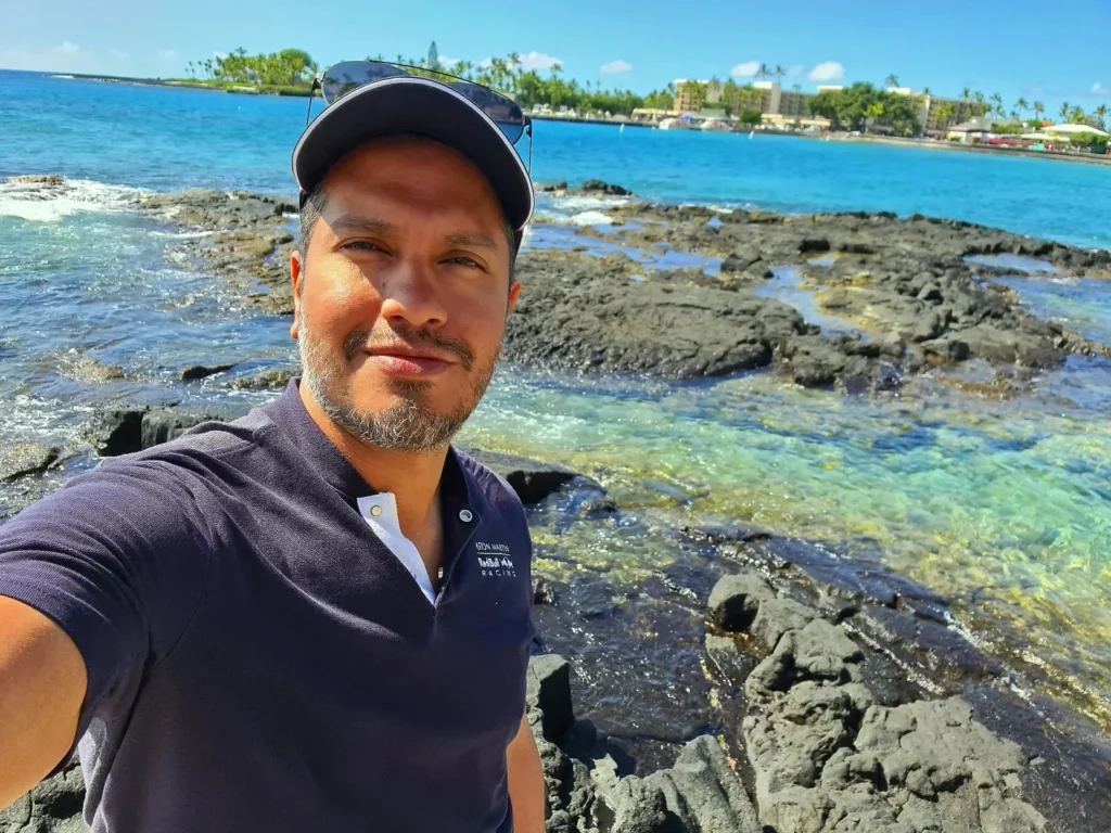 Cruising with Danny and Peter, Holland America Line, Koningsdam, Kona, Hawaii, United-States | A vibrant scene showcasing the beauty of Kona Hawaii, featuring secluded beaches with soft sand and crystal-clear waters, colorful storefronts along the bustling streets, and breathtaking scenic views of the Kona coast during sunset. The image captures the essence of Exploring Kona's Island Charm, highlighting local culture with hula dancers and delicious Hawaiian cuisine served at a beachfront restaurant.