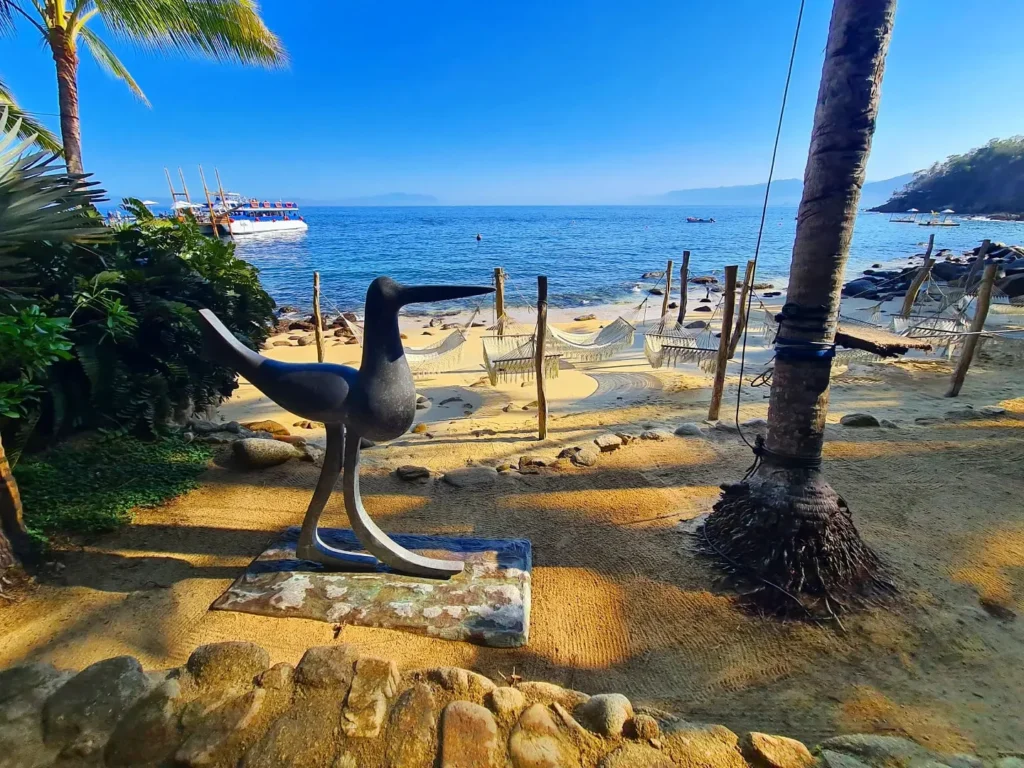 Cruising with Danny and Peter, Holland America Line, Koningsdam, Puerto Vallarta, Mexico | Las Caletas Beach in Puerto Vallarta featuring serene sandy shores, lush tropical greenery, and guests enjoying a relaxing beach day. The scene captures the essence of a secluded beach getaway with clear blue waters, vibrant Mexican cuisine, and the tranquil atmosphere of this hidden gem.