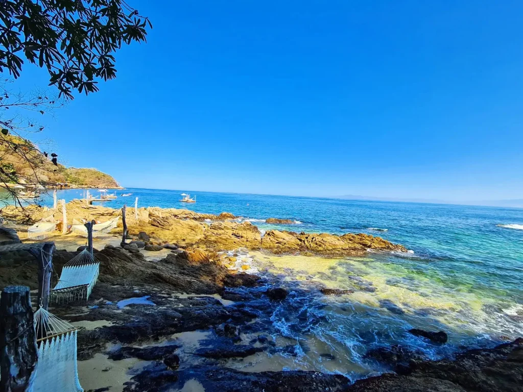 Cruising with Danny and Peter, Holland America Line, Koningsdam, Puerto Vallarta, Mexico | Las Caletas Beach in Puerto Vallarta featuring serene sandy shores, lush tropical greenery, and guests enjoying a relaxing beach day. The scene captures the essence of a secluded beach getaway with clear blue waters, vibrant Mexican cuisine, and the tranquil atmosphere of this hidden gem.