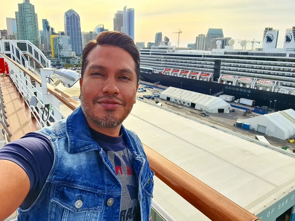 Cruising with Danny and Peter, Holland America Line, Koningsdam, San Diego, Los Angeles, California, United States | A stunning view of the Pacific coastline during a sunset sojourn from San Diego to Santa Monica, featuring vibrant hues of orange and pink in the sky, palm trees lining the oceanfront promenade, and the iconic Santa Monica Pier in the distance, capturing the essence of a scenic beach getaway and the California golden hour.