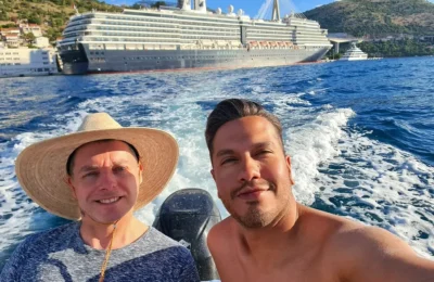 Cruising with Danny and Peter, Holland America Line, Oosterdam, Dubrovnik, Croatia | A stunning view of Dubrovnik's iconic city walls and terracotta rooftops during a private boat tour on the Adriatic Sea, showcasing the serene coastline and picturesque landscapes, highlighting the beauty of a Dubrovnik sailing trip.