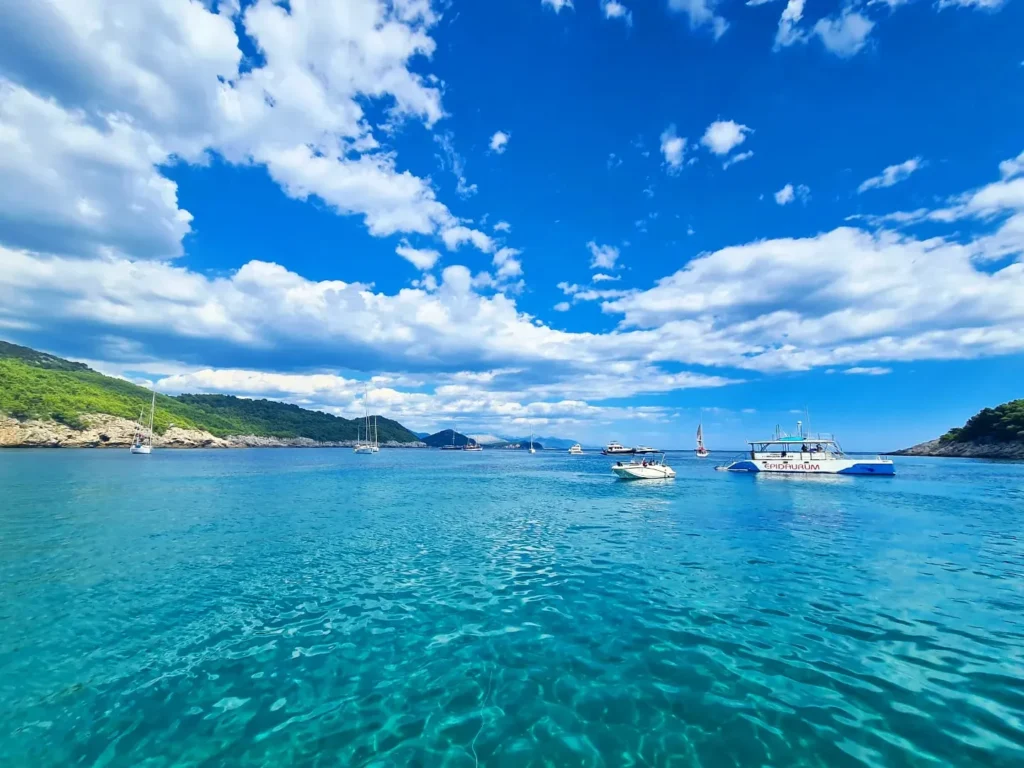 Cruising with Danny and Peter, Holland America Line, Oosterdam, Dubrovnik, Croatia | A stunning view of Dubrovnik's iconic city walls and terracotta rooftops during a private boat tour on the Adriatic Sea, showcasing the serene coastline and picturesque landscapes, highlighting the beauty of a Dubrovnik sailing trip.