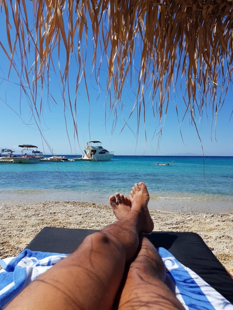 Cruising with Danny and Peter, Holland America Line, Koningsdam, Mykonos, Greece | Scenic view of Elia Beach in Mykonos, showcasing crystal-clear waters, soft sands, and the stunning Aegean Sea backdrop, with travelers enjoying their Mykonos Greece travel experience, exploring the serene beach and vibrant Mykonos Town attractions.