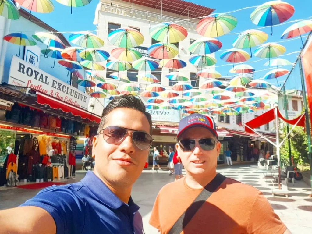 Cruising with Danny and Peter, Holland America Line, Koningsdam, Kusadasi, Ephesus, Turkey | A picturesque view of Kuşadası Beach showcasing soft golden sands and crystal-clear Aegean Sea waters, vibrant local markets filled with traditional Turkish crafts, and visitors savoring authentic Turkish cuisine at a charming café, highlighting the cultural exploration and seaside relaxation of a perfect Kuşadası Beach Day on the Turkish Riviera.