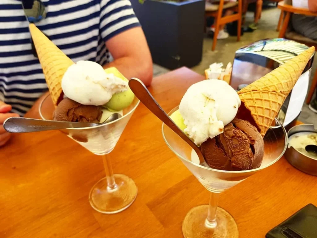 Cruising with Danny and Peter, Holland America Line, Koningsdam, Kusadasi, Ephesus, Turkey | A picturesque view of Kuşadası Beach showcasing soft golden sands and crystal-clear Aegean Sea waters, vibrant local markets filled with traditional Turkish crafts, and visitors savoring authentic Turkish cuisine at a charming café, highlighting the cultural exploration and seaside relaxation of a perfect Kuşadası Beach Day on the Turkish Riviera.