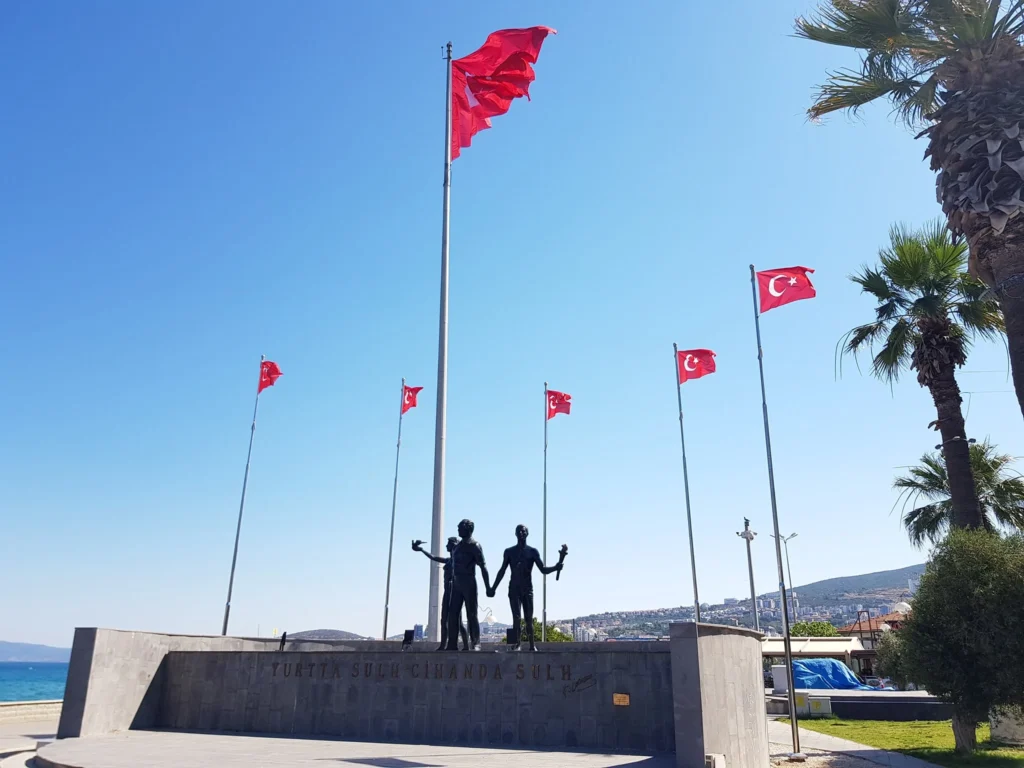 Cruising with Danny and Peter, Holland America Line, Koningsdam, Kusadasi, Ephesus, Turkey | A picturesque view of Kuşadası Beach showcasing soft golden sands and crystal-clear Aegean Sea waters, vibrant local markets filled with traditional Turkish crafts, and visitors savoring authentic Turkish cuisine at a charming café, highlighting the cultural exploration and seaside relaxation of a perfect Kuşadası Beach Day on the Turkish Riviera.