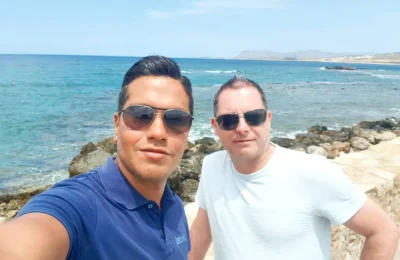 Cruising with Danny and Peter, Holland America Line, Koningsdam, Souda, Chania, Greece | Scenic view of Souda Port with fishing boats and distant mountains, charming streets of Chania with Venetian architecture, and vibrant Crete local markets during a Greek Island Adventure.