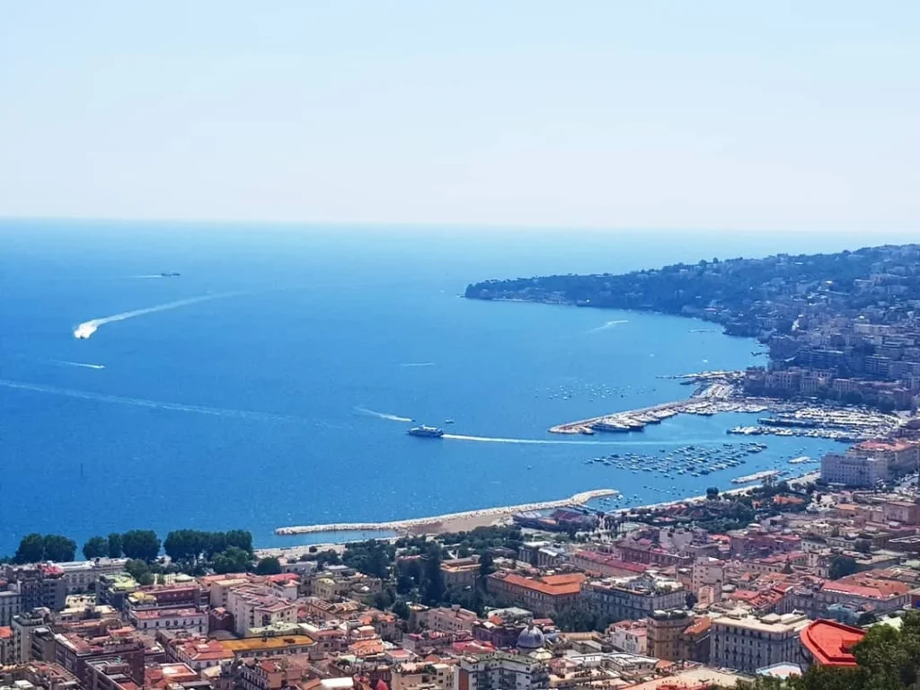 Cruising with Danny and Peter, Holland America Line, Koningsdam, Naples, Pompeii, Amalfi, Italy | View of the Stromboli volcanic eruption at night from the Koningsdam deck during an Italy volcano cruise experience, showcasing the fiery bursts illuminating the sky, with Naples bay scenery in the background and a group of travelers admiring the spectacle.