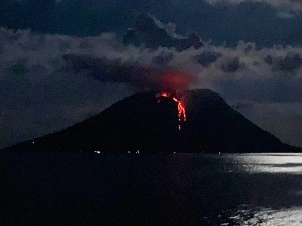 Cruising with Danny and Peter, Holland America Line, Koningsdam, Naples, Pompeii, Amalfi, Italy | View of the Stromboli volcanic eruption at night from the Koningsdam deck during an Italy volcano cruise experience, showcasing the fiery bursts illuminating the sky, with Naples bay scenery in the background and a group of travelers admiring the spectacle.
