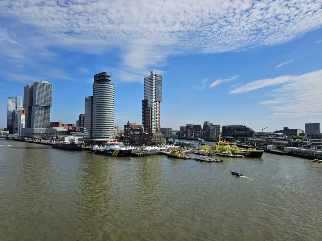 Cruising with Danny and Peter, P&O Ferries, Pride of Rotterdam, Spido, James Cook, Rotterdam, The Netherlands | A stunning Rotterdam mini cruise experience during World Port Days, starting from Beneluxhaven aboard the Pride of Rotterdam, surrounded by massive container ships and barges. Highlights include breathtaking views of the iconic Erasmus Bridge with its swan-like cables over the Nieuwe Maas river, and a sunset scene at Wilhelminakade with its modern skyscrapers and bustling port activities. The evening Spido harbor tour on the James Cook offered an illuminated view of Rotterdam's busy harbor, passing the majestic SS Rotterdam ship, a symbol of the city’s maritime heritage. The day concluded with a vibrant boat parade featuring illuminated vessels, followed by a spectacular fireworks display lighting up the Rotterdam skyline.