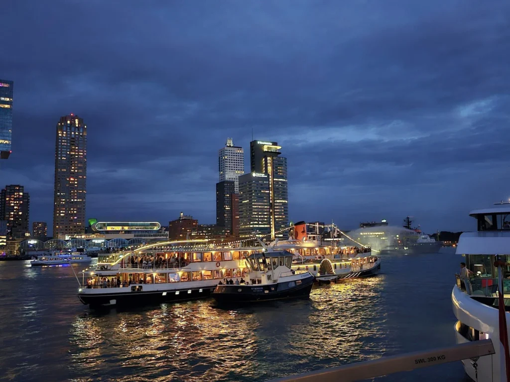 Cruising with Danny and Peter, P&O Ferries, Pride of Rotterdam, Spido, James Cook, Rotterdam, The Netherlands | A stunning Rotterdam mini cruise experience during World Port Days, starting from Beneluxhaven aboard the Pride of Rotterdam, surrounded by massive container ships and barges. Highlights include breathtaking views of the iconic Erasmus Bridge with its swan-like cables over the Nieuwe Maas river, and a sunset scene at Wilhelminakade with its modern skyscrapers and bustling port activities. The evening Spido harbor tour on the James Cook offered an illuminated view of Rotterdam's busy harbor, passing the majestic SS Rotterdam ship, a symbol of the city’s maritime heritage. The day concluded with a vibrant boat parade featuring illuminated vessels, followed by a spectacular fireworks display lighting up the Rotterdam skyline.