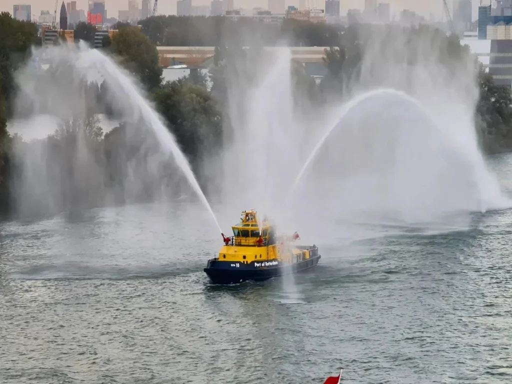 Cruising with Danny and Peter, Holland America Line, Rotterdam, Rotterdam, The Netherlands | A stunning view of the M.S. Rotterdam as it sails away from Rotterdam, celebrating Holland America 150th Anniversary with historic ships in the background. The sunset casts a golden glow on the luxury ocean liner, capturing the excitement of our transatlantic voyage from Rotterdam to New York. A special anniversary menu and Holland America memorabilia highlight this remarkable journey.