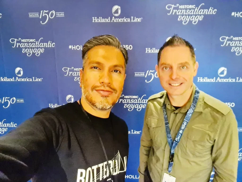 Cruising with Danny and Peter, Holland America Line, Rotterdam, Rotterdam, The Netherlands | A stunning view of the M.S. Rotterdam as it sails away from Rotterdam, celebrating Holland America 150th Anniversary with historic ships in the background. The sunset casts a golden glow on the luxury ocean liner, capturing the excitement of our transatlantic voyage from Rotterdam to New York. A special anniversary menu and Holland America memorabilia highlight this remarkable journey.