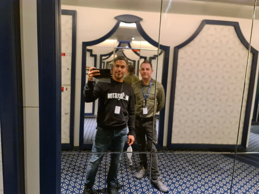 Cruising with Danny and Peter, Holland America Line, Rotterdam, Rotterdam, The Netherlands | A stunning view of the M.S. Rotterdam as it sails away from Rotterdam, celebrating Holland America 150th Anniversary with historic ships in the background. The sunset casts a golden glow on the luxury ocean liner, capturing the excitement of our transatlantic voyage from Rotterdam to New York. A special anniversary menu and Holland America memorabilia highlight this remarkable journey.