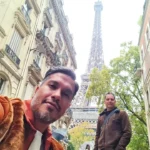 Cruising with Danny and Peter, Holland America Line, Rotterdam, Le Havre, Paris, France | A scenic view of the Eiffel Tower during a Paris day trip from Le Havre, showcasing the iconic landmark surrounded by blooming gardens, a relaxing Seine River cruise with passengers enjoying lunch, and hidden photo spots capturing the beauty of Paris.