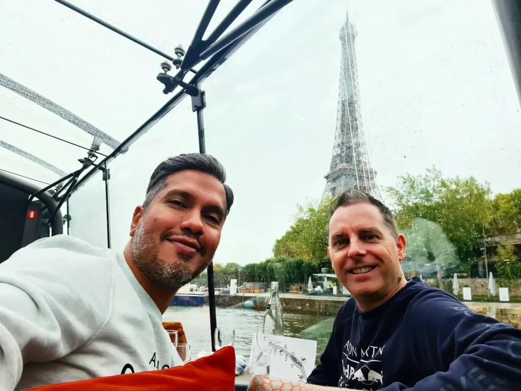 Cruising with Danny and Peter, Holland America Line, Rotterdam, Le Havre, Paris, France | A scenic view of the Eiffel Tower during a Paris day trip from Le Havre, showcasing the iconic landmark surrounded by blooming gardens, a relaxing Seine River cruise with passengers enjoying lunch, and hidden photo spots capturing the beauty of Paris.