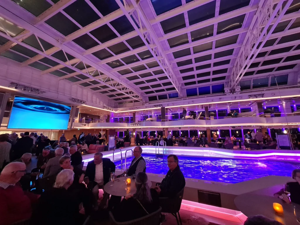 Cruising with Danny and Peter, Holland America Line, Rotterdam, Atlantic Ocean, Sea Day | Guests enjoying the first sea day on the Holland America Line 150th Anniversary Cruise aboard the Rotterdam, featuring scenic Atlantic Ocean views, elegant dining at the Pinnacle Grill, onboard events like the Mariners Society meeting on the Lido Deck, and morning breakfast selections. A memorable day at sea during Holland America Line’s milestone voyage celebration.