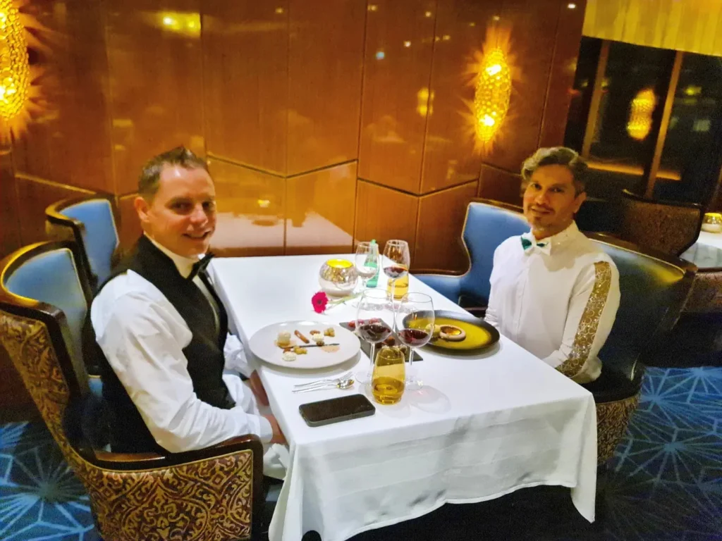 Cruising with Danny and Peter, Holland America Line, Rotterdam, Atlantic Ocean, Sea Day | A beautifully plated dish from the Taste of De Librije dinner aboard the Rotterdam, featuring Jonnie Boer cuisine, including caviar egg, king fish, and oysters, paired with Cloudy Bay Sauvignon Blanc. The elegant dining setup highlights the luxurious atmosphere of Holland America Line's Pinnacle Grill during this exquisite transatlantic cruise dinner.