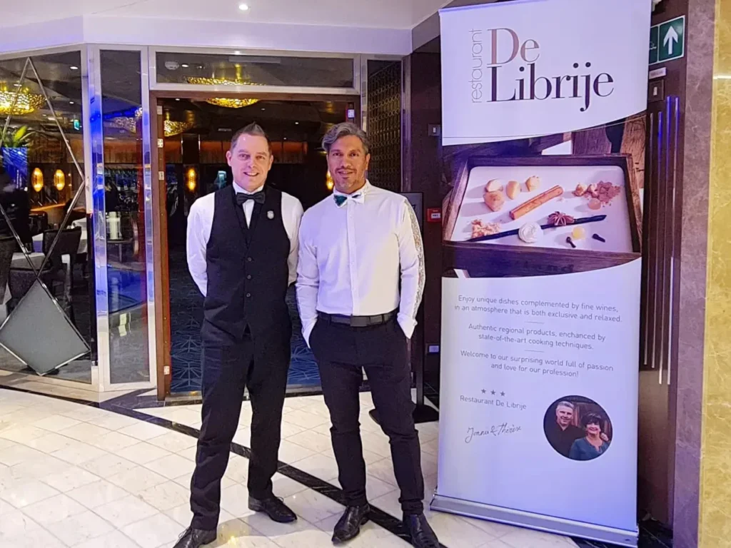 Cruising with Danny and Peter, Holland America Line, Rotterdam, Atlantic Ocean, Sea Day | A beautifully plated dish from the Taste of De Librije dinner aboard the Rotterdam, featuring Jonnie Boer cuisine, including caviar egg, king fish, and oysters, paired with Cloudy Bay Sauvignon Blanc. The elegant dining setup highlights the luxurious atmosphere of Holland America Line's Pinnacle Grill during this exquisite transatlantic cruise dinner.