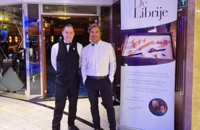 Cruising with Danny and Peter, Holland America Line, Rotterdam, Atlantic Ocean, Sea Day | A beautifully plated dish from the Taste of De Librije dinner aboard the Rotterdam, featuring Jonnie Boer cuisine, including caviar egg, king fish, and oysters, paired with Cloudy Bay Sauvignon Blanc. The elegant dining setup highlights the luxurious atmosphere of Holland America Line's Pinnacle Grill during this exquisite transatlantic cruise dinner.