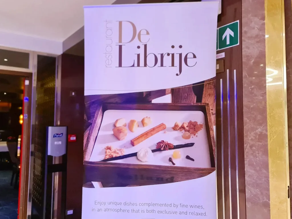 Cruising with Danny and Peter, Holland America Line, Rotterdam, Atlantic Ocean, Sea Day | A beautifully plated dish from the Taste of De Librije dinner aboard the Rotterdam, featuring Jonnie Boer cuisine, including caviar egg, king fish, and oysters, paired with Cloudy Bay Sauvignon Blanc. The elegant dining setup highlights the luxurious atmosphere of Holland America Line's Pinnacle Grill during this exquisite transatlantic cruise dinner.