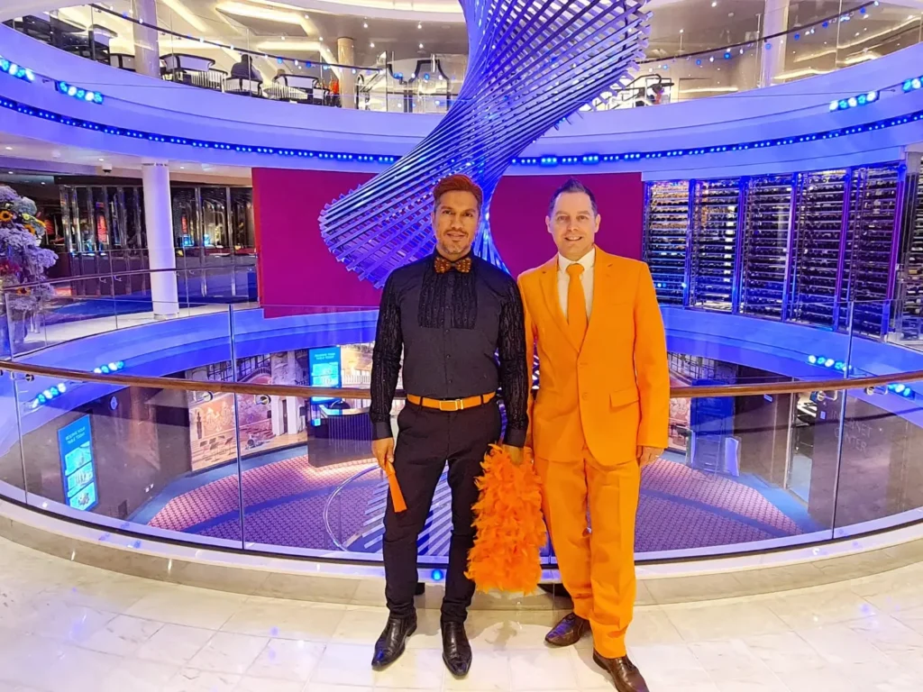 Cruising with Danny and Peter, Holland America Line, Rotterdam, Atlantic Ocean, Sea Day | Guests celebrating the Orange Party Holland America 150th Anniversary aboard the MS Rotterdam, enjoying live music, Dutch treats like Kapsalon, Poffertjes, and Kleine Appeltaart, while wearing orange attire in honor of Dutch heritage and the Holland America anniversary party.