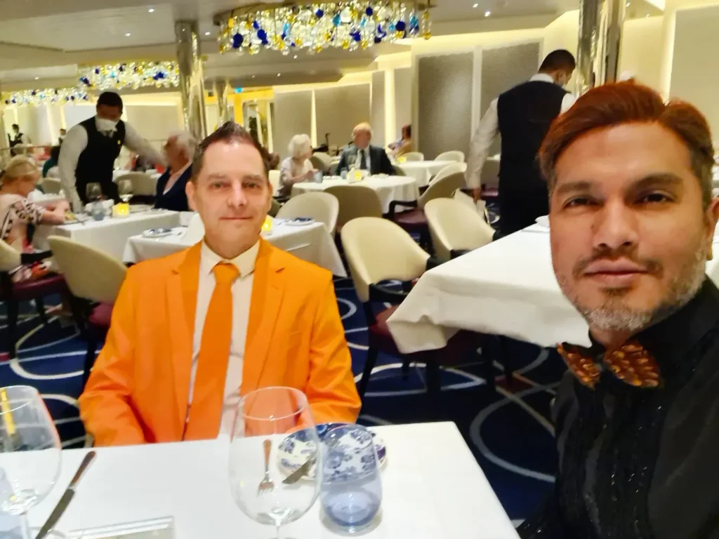 Cruising with Danny and Peter, Holland America Line, Rotterdam, Atlantic Ocean, Sea Day | Guests celebrating the Orange Party Holland America 150th Anniversary aboard the MS Rotterdam, enjoying live music, Dutch treats like Kapsalon, Poffertjes, and Kleine Appeltaart, while wearing orange attire in honor of Dutch heritage and the Holland America anniversary party.