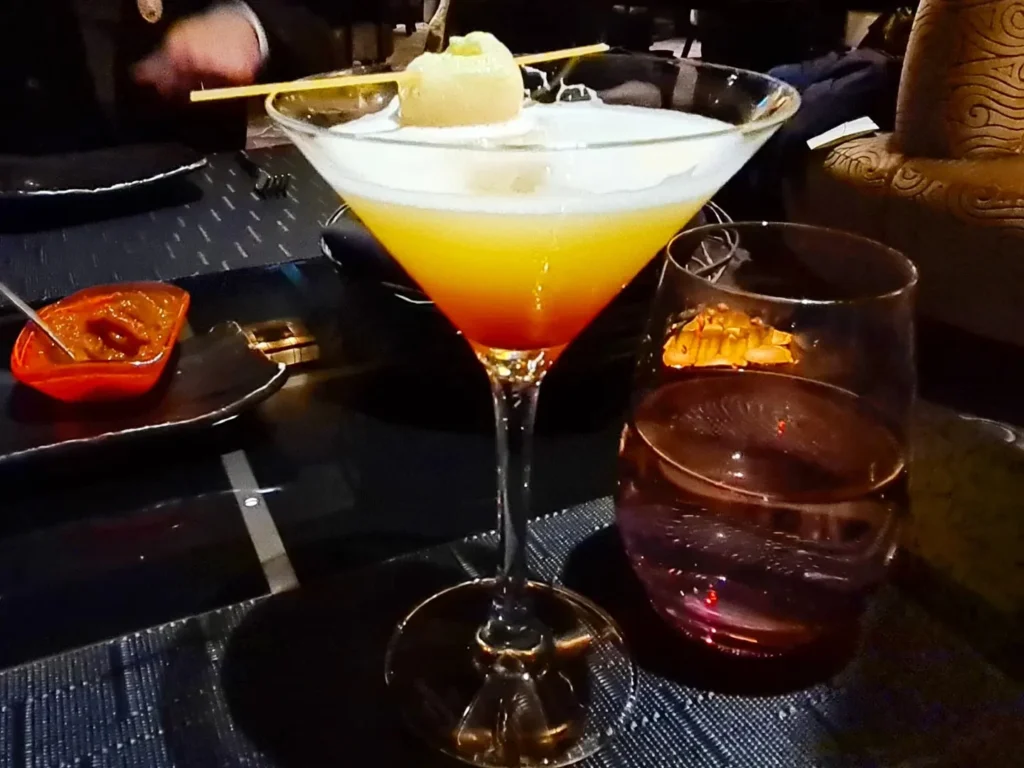 Cruising with Danny and Peter, Holland America Line, Rotterdam, Atlantic Ocean, Sea Day | Indonesian Rijsttafel at Sea served at the Tamarind restaurant aboard the Rotterdam cruise, showcasing vibrant dishes including Soto Ayam Madura, Nasi Goreng, and Pork Sate, alongside a Wasabi martini and Jalapeño martini, highlighting the unique culinary experience and ambiance of specialty restaurants on the cruise.