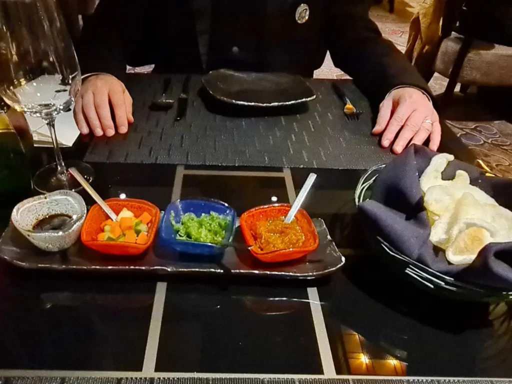 Cruising with Danny and Peter, Holland America Line, Rotterdam, Atlantic Ocean, Sea Day | Indonesian Rijsttafel at Sea served at the Tamarind restaurant aboard the Rotterdam cruise, showcasing vibrant dishes including Soto Ayam Madura, Nasi Goreng, and Pork Sate, alongside a Wasabi martini and Jalapeño martini, highlighting the unique culinary experience and ambiance of specialty restaurants on the cruise.