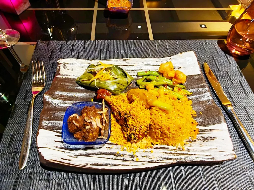 Cruising with Danny and Peter, Holland America Line, Rotterdam, Atlantic Ocean, Sea Day | Indonesian Rijsttafel at Sea served at the Tamarind restaurant aboard the Rotterdam cruise, showcasing vibrant dishes including Soto Ayam Madura, Nasi Goreng, and Pork Sate, alongside a Wasabi martini and Jalapeño martini, highlighting the unique culinary experience and ambiance of specialty restaurants on the cruise.