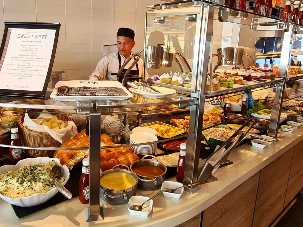 Cruising with Danny and Peter, Holland America Line, Rotterdam, Atlantic Ocean, Sea Day | Indonesian Rijsttafel at Sea served at the Tamarind restaurant aboard the Rotterdam cruise, showcasing vibrant dishes including Soto Ayam Madura, Nasi Goreng, and Pork Sate, alongside a Wasabi martini and Jalapeño martini, highlighting the unique culinary experience and ambiance of specialty restaurants on the cruise.