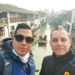 Cruising with Danny and Peter, Holland America Line, Westerdam, Shanghai, China | Serene canal view in Shanghai Watertown, showcasing traditional Chinese architecture and vibrant red lanterns, with a scenic boat ride through historic waterways and lush gardens, capturing the timeless charm and cultural heritage of Shanghai's ancient town.