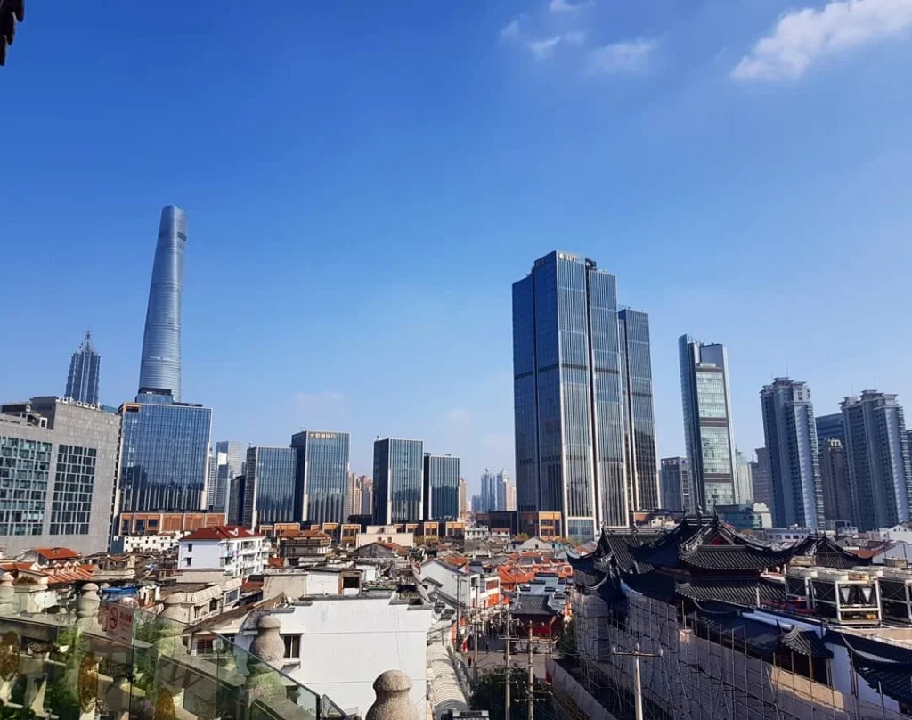 Cruising with Danny and Peter, Holland America Line, Westerdam, Shanghai, China | A guide leading a group through historic landmarks in Shanghai, showcasing the vibrant cityscape, modern skyscrapers, and traditional architecture. The group enjoys a Chinese tea ceremony, tasting various teas in a serene teahouse, capturing the essence of an unforgettable Shanghai Private Tour and Tea Tasting Experience.