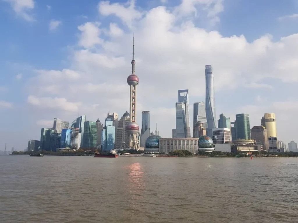 Cruising with Danny and Peter, Holland America Line, Westerdam, Shanghai, China | A guide leading a group through historic landmarks in Shanghai, showcasing the vibrant cityscape, modern skyscrapers, and traditional architecture. The group enjoys a Chinese tea ceremony, tasting various teas in a serene teahouse, capturing the essence of an unforgettable Shanghai Private Tour and Tea Tasting Experience.