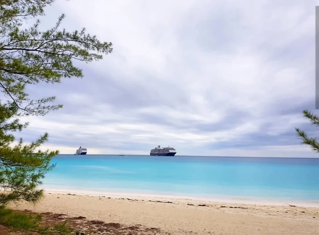 A Slice of Paradise: Experience the Bahamas Beach Paradise of Half Moon Cay 5 Cruising with Danny and Peter, Holland America Line, Zuiderdam, Half Moon Cay, Bahamas | Stunning view of Half Moon Cay showcasing its pristine sandy shores, vibrant turquoise waters, and swaying palm trees, epitomizing a Bahamas beach paradise. Visitors enjoy exciting water activities like kayaking and jet skiing, while others relax on sun-soaked beaches, capturing the essence of this tropical island paradise.