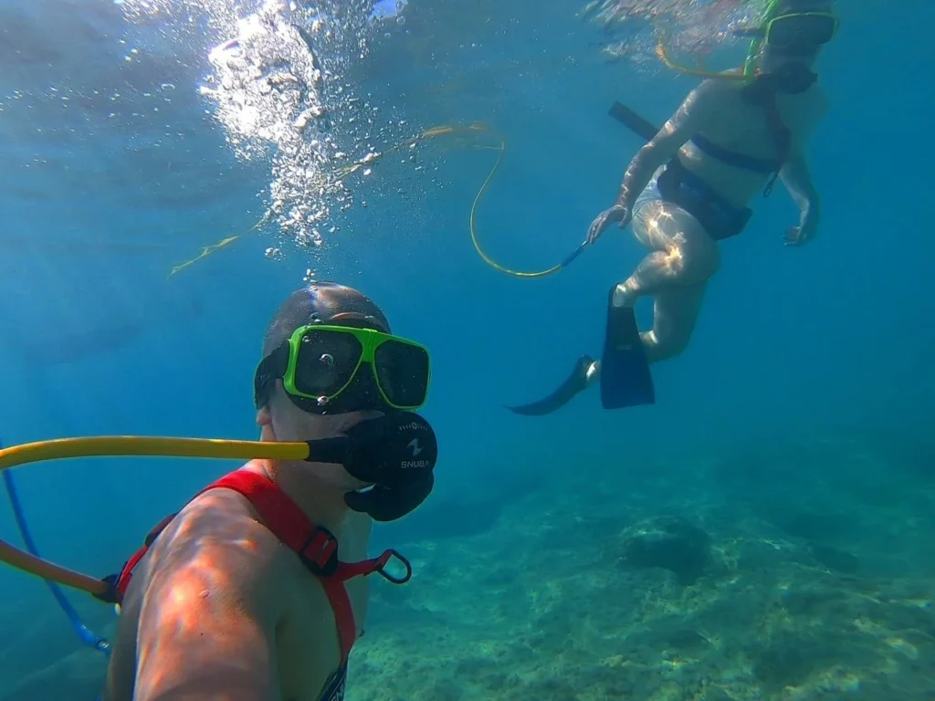 Cruising with Danny and Peter, Holland America Line, Zuiderdam, Grand Turk, Turks And Caicos | A group of adventurers enjoying a Snuba adventure in Grand Turk, exploring vibrant marine life and colorful coral reefs. The clear turquoise waters showcase the underwater ecosystem as participants breathe effortlessly through their Snuba equipment, immersing themselves in this unforgettable Caribbean snorkeling experience.