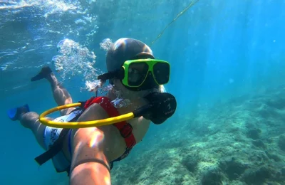 Cruising with Danny and Peter, Holland America Line, Zuiderdam, Grand Turk, Turks And Caicos | A group of adventurers enjoying a Snuba adventure in Grand Turk, exploring vibrant marine life and colorful coral reefs. The clear turquoise waters showcase the underwater ecosystem as participants breathe effortlessly through their Snuba equipment, immersing themselves in this unforgettable Caribbean snorkeling experience.