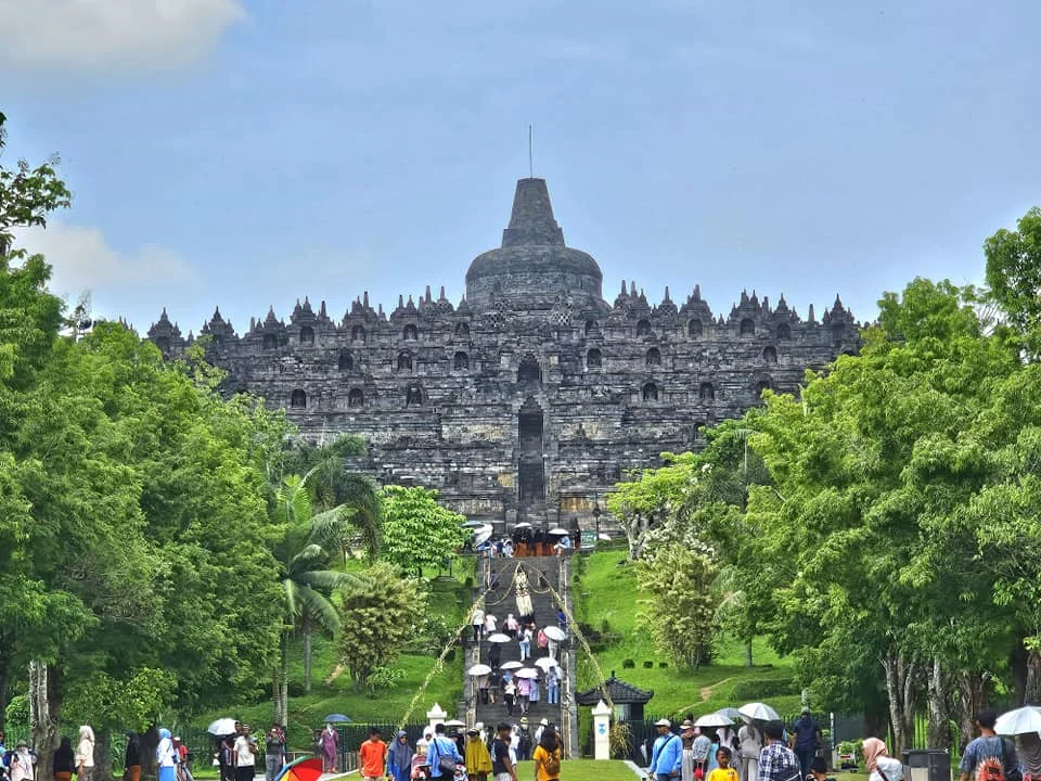 Cruising with Danny and Peter, Holland America Line, Westerdam, Semarang, Java, Indonesia, Borobudur Temple Cruise, Java Adventure | Panoramic view of Borobudur during a Borobudur Temple Cruise, showcasing the UNESCO Buddhist Temple amidst Central Java’s lush hills, with the Westerdam ship docked for the Holland America Westerdam Borobudur Tour, a Luxury Cruise Java adventure in Holland America Far East. Close-up of stupas and Buddha statues at Borobudur, reflecting Mahayana Buddhist Heritage, alongside a vibrant market scene from a Semarang Java Tour, part of an Indonesian Cultural Journey. Travelers explore this Borobudur Pilgrimage Site on a Central Java Travel excursion, enjoying a stunning sunset over the 9th-Century Temple Exploration, with detailed stone reliefs of the UNESCO Buddhist Temple and relaxation on the Westerdam deck during a Westerdam Cruise Indonesia.