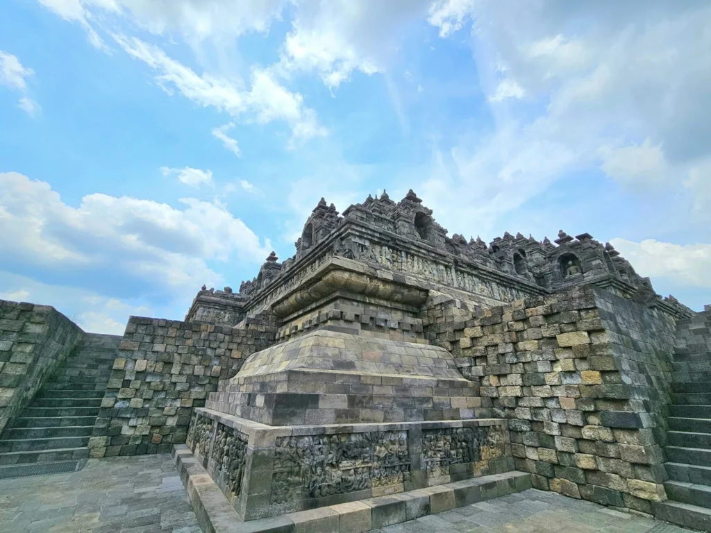 Cruising with Danny and Peter, Holland America Line, Westerdam, Semarang, Java, Indonesia, Borobudur Temple Cruise, Java Adventure | Panoramic view of Borobudur during a Borobudur Temple Cruise, showcasing the UNESCO Buddhist Temple amidst Central Java’s lush hills, with the Westerdam ship docked for the Holland America Westerdam Borobudur Tour, a Luxury Cruise Java adventure in Holland America Far East. Close-up of stupas and Buddha statues at Borobudur, reflecting Mahayana Buddhist Heritage, alongside a vibrant market scene from a Semarang Java Tour, part of an Indonesian Cultural Journey. Travelers explore this Borobudur Pilgrimage Site on a Central Java Travel excursion, enjoying a stunning sunset over the 9th-Century Temple Exploration, with detailed stone reliefs of the UNESCO Buddhist Temple and relaxation on the Westerdam deck during a Westerdam Cruise Indonesia.