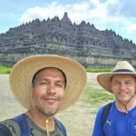 Cruising with Danny and Peter, Holland America Line, Westerdam, Semarang, Java, Indonesia, Borobudur Temple Cruise, Java Adventure | Panoramic view of Borobudur during a Borobudur Temple Cruise, showcasing the UNESCO Buddhist Temple amidst Central Java’s lush hills, with the Westerdam ship docked for the Holland America Westerdam Borobudur Tour, a Luxury Cruise Java adventure in Holland America Far East. Close-up of stupas and Buddha statues at Borobudur, reflecting Mahayana Buddhist Heritage, alongside a vibrant market scene from a Semarang Java Tour, part of an Indonesian Cultural Journey. Travelers explore this Borobudur Pilgrimage Site on a Central Java Travel excursion, enjoying a stunning sunset over the 9th-Century Temple Exploration, with detailed stone reliefs of the UNESCO Buddhist Temple and relaxation on the Westerdam deck during a Westerdam Cruise Indonesia.