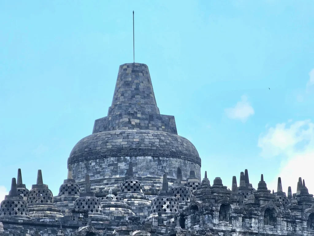Cruising with Danny and Peter, Holland America Line, Westerdam, Semarang, Java, Indonesia, Borobudur Temple Cruise, Java Adventure | Panoramic view of Borobudur during a Borobudur Temple Cruise, showcasing the UNESCO Buddhist Temple amidst Central Java’s lush hills, with the Westerdam ship docked for the Holland America Westerdam Borobudur Tour, a Luxury Cruise Java adventure in Holland America Far East. Close-up of stupas and Buddha statues at Borobudur, reflecting Mahayana Buddhist Heritage, alongside a vibrant market scene from a Semarang Java Tour, part of an Indonesian Cultural Journey. Travelers explore this Borobudur Pilgrimage Site on a Central Java Travel excursion, enjoying a stunning sunset over the 9th-Century Temple Exploration, with detailed stone reliefs of the UNESCO Buddhist Temple and relaxation on the Westerdam deck during a Westerdam Cruise Indonesia.