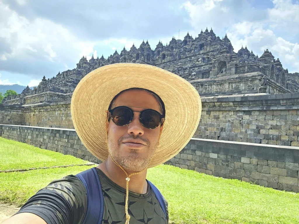 Cruising with Danny and Peter, Holland America Line, Westerdam, Semarang, Java, Indonesia, Borobudur Temple Cruise, Java Adventure | Panoramic view of Borobudur during a Borobudur Temple Cruise, showcasing the UNESCO Buddhist Temple amidst Central Java’s lush hills, with the Westerdam ship docked for the Holland America Westerdam Borobudur Tour, a Luxury Cruise Java adventure in Holland America Far East. Close-up of stupas and Buddha statues at Borobudur, reflecting Mahayana Buddhist Heritage, alongside a vibrant market scene from a Semarang Java Tour, part of an Indonesian Cultural Journey. Travelers explore this Borobudur Pilgrimage Site on a Central Java Travel excursion, enjoying a stunning sunset over the 9th-Century Temple Exploration, with detailed stone reliefs of the UNESCO Buddhist Temple and relaxation on the Westerdam deck during a Westerdam Cruise Indonesia.