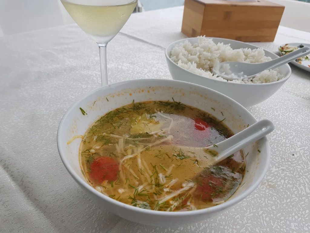 Cruising with Danny and Peter, Holland America Line, Westerdam, Halong Bay, Vietnam | A stunning view of the Hạ Long Bay Yacht cruising through emerald waters, surrounded by majestic limestone karsts. Guests enjoy Vietnamese seafood dining on the deck while kayaking in Hạ Long Bay. The private yacht tour showcases the beauty of this UNESCO World Heritage site.