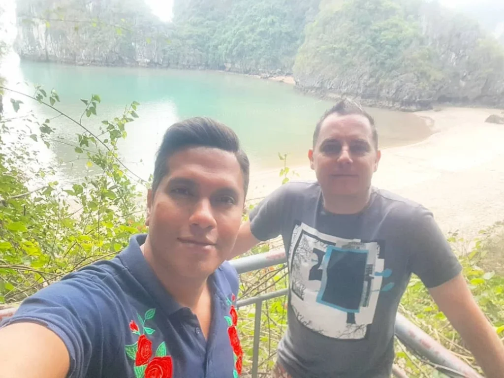 Cruising with Danny and Peter, Holland America Line, Westerdam, Halong Bay, Vietnam | A stunning view of the Hạ Long Bay Yacht cruising through emerald waters, surrounded by majestic limestone karsts. Guests enjoy Vietnamese seafood dining on the deck while kayaking in Hạ Long Bay. The private yacht tour showcases the beauty of this UNESCO World Heritage site.